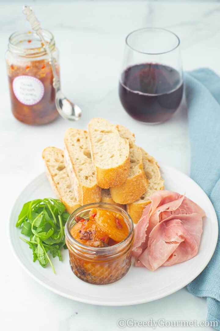 Dried apricot chutney served alongside bread, ham and a small glass of red wine.