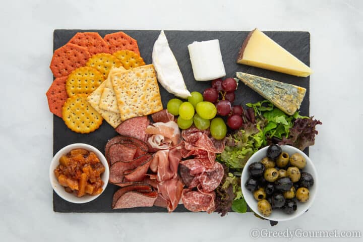 Charcuterie board with quince chutney, crackers, cheeses, olives and meats.