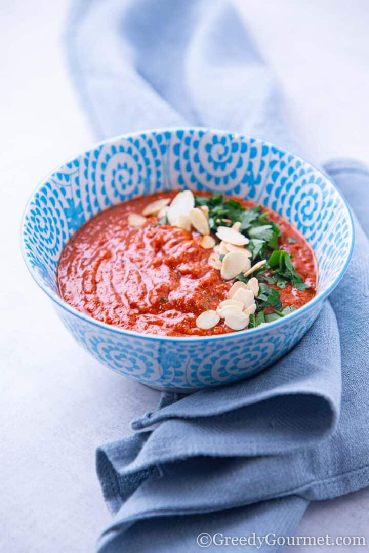 Romesco Sauce in blue bowl with nuts and herbs