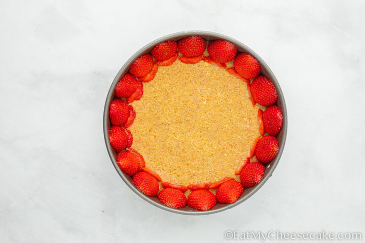 Strawberries lining inside of a cheesecake pan.