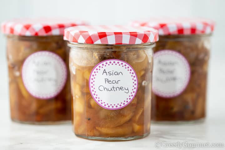 Asian pear chutney in glass jars with a red lid