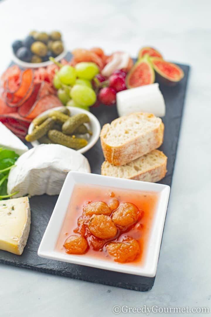 White Grape Chutney with Mint on cheeseboard alongside bread, fruit, cheese and meats.