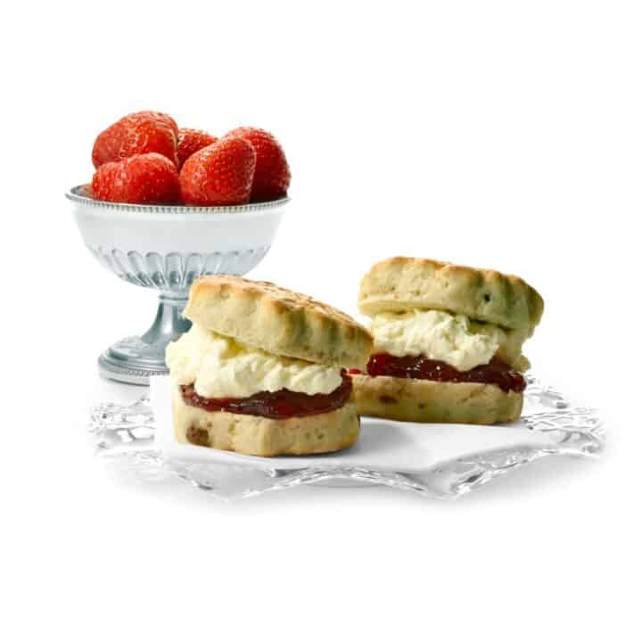 Platter of scones with jam and clotted cream alongside a goblet of strawberries