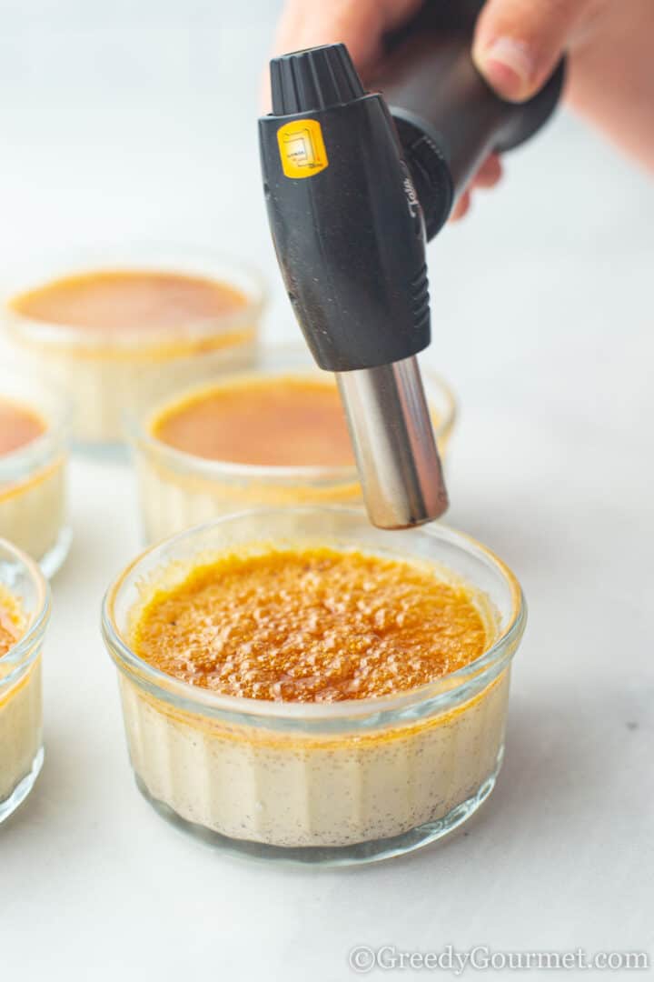 Eggnog crème brûlée being browned by blowtorch