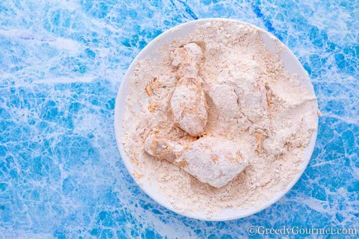 coating chicken in flour.