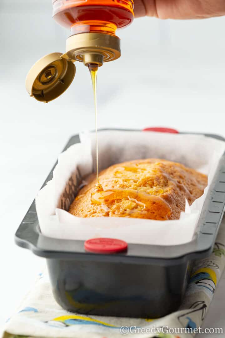 pouring golden syrup over the loaf cake.