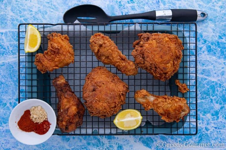 sous vide fried chicken on a cooling rack with lemon wedges.