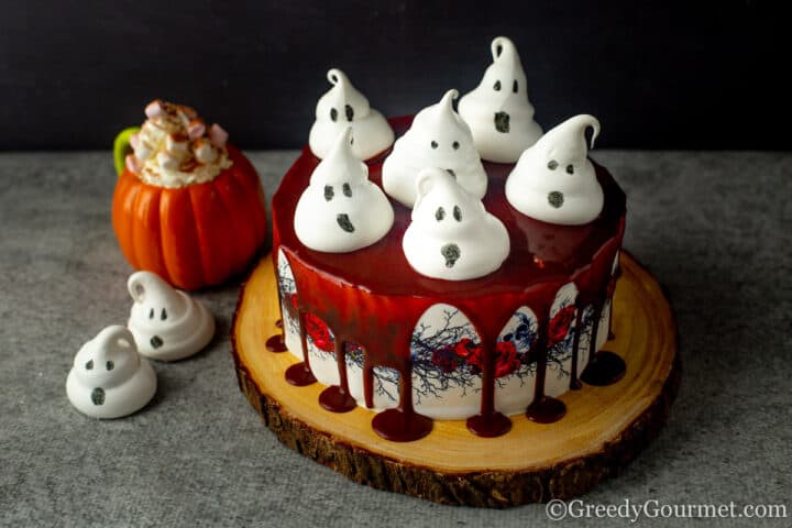 Meringue Ghosts on cake with hot chocolate in pumpkin mug