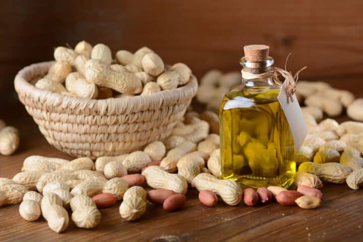Peanuts in bowl and a bottle of peanut oil