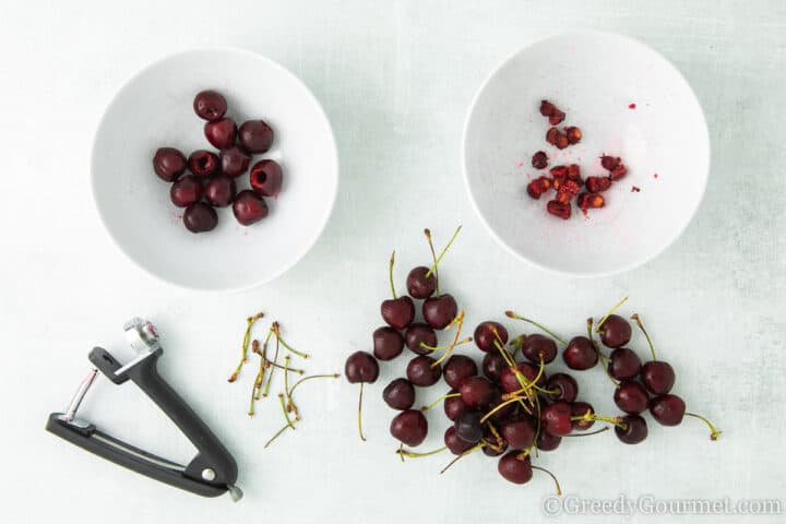 cherry pitter next to unpitted and pitted cherries