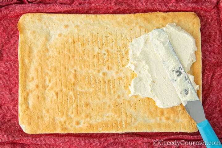 Spreading buttercream onto a vanilla sheet cake