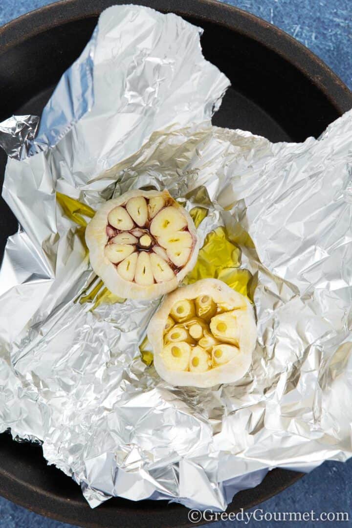 Garlic bulbs in oil in in tin foil.