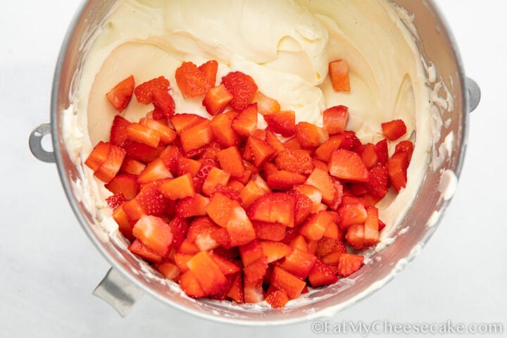 cut up strawberries in cheesecake batter
