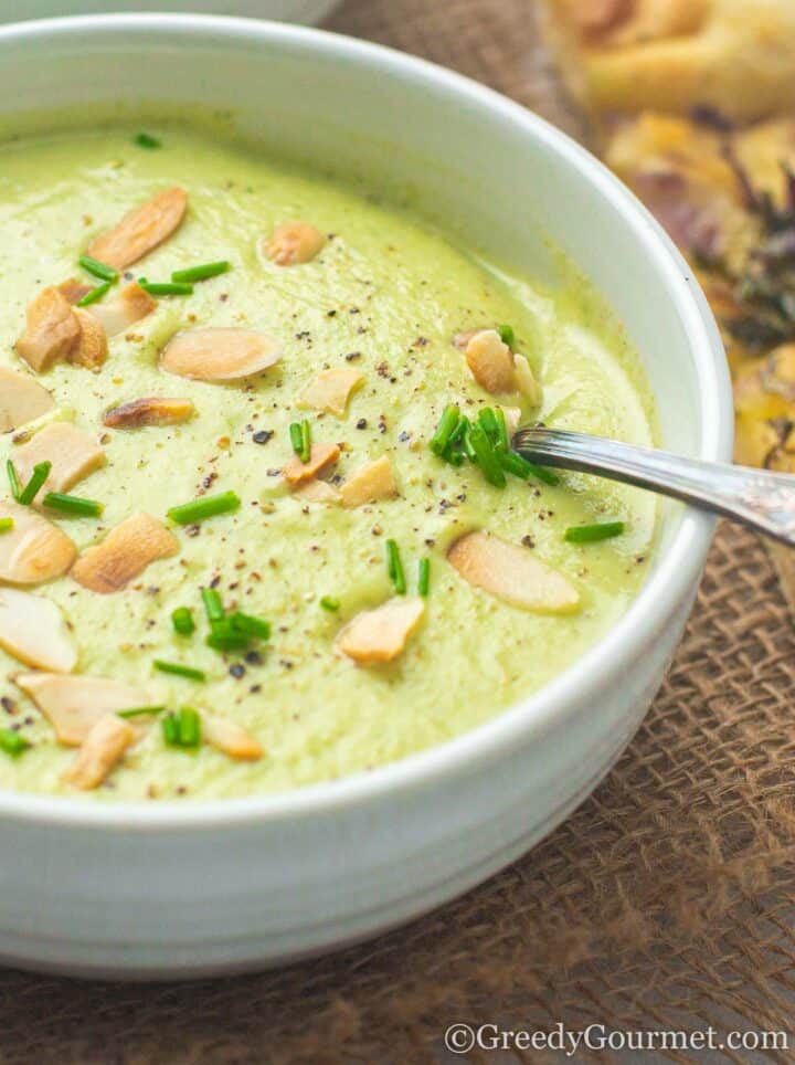 bowl of green soup sprinkled with almonds.