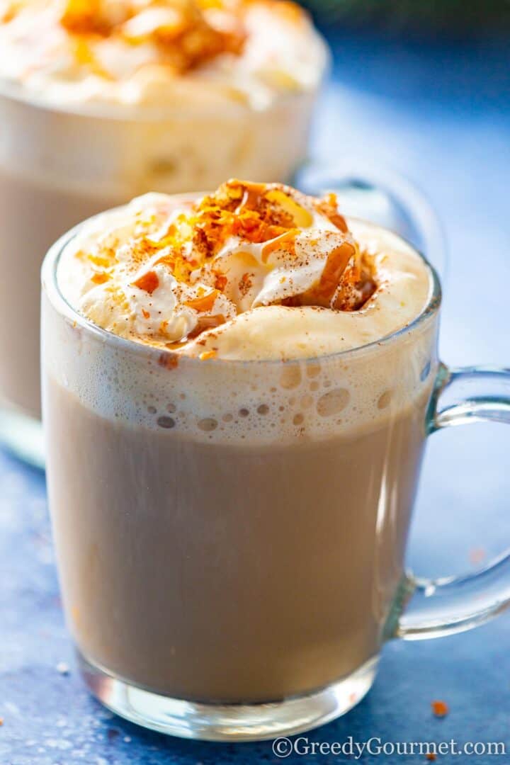 eggnog latte in a glass mug with caramel drizzle and cinnamon 