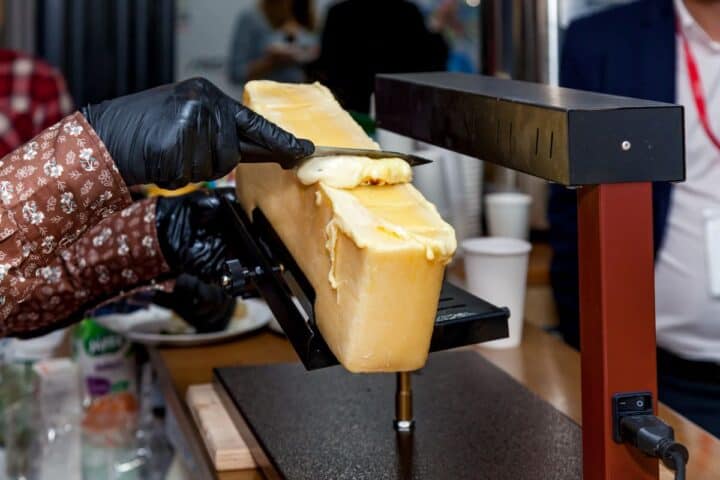 Person using a knife to scrape melted raclette cheese