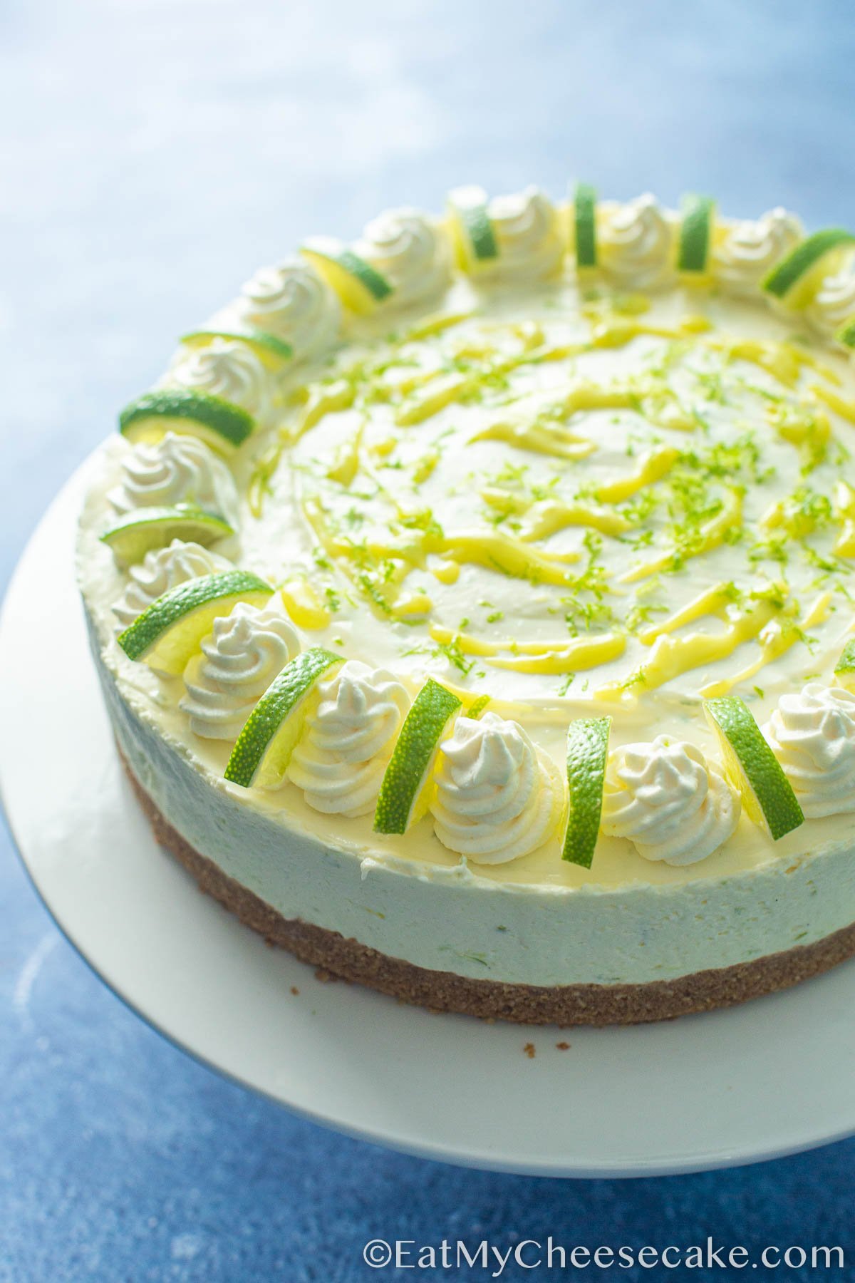 Decorated no bake lime cheesecake with lime curd and lime zest and lime wedges.