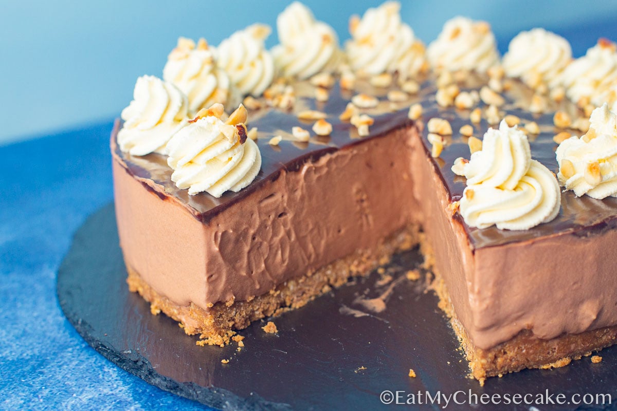 Nutella cheesecake with cream swirl decorations and sprinkled with nuts.