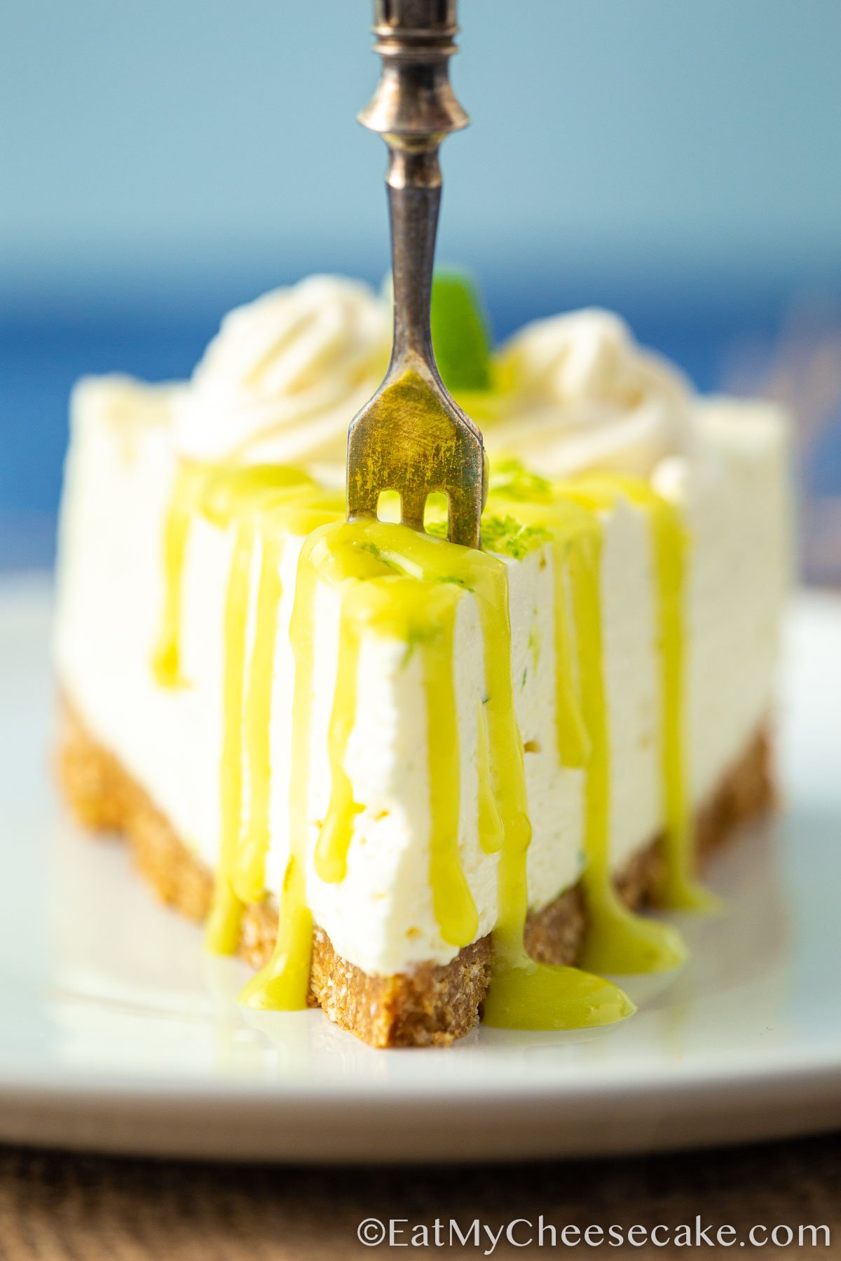 Slice of no bake lime cheesecake with lime curd drizzled on top.