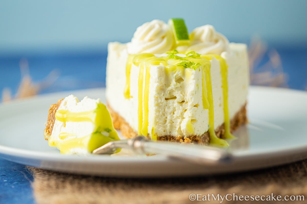 Slice of no bake lime cheesecake with lime curd drizzled on top with a fork.