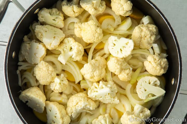 Adding raw vegetables to a cooking pot.