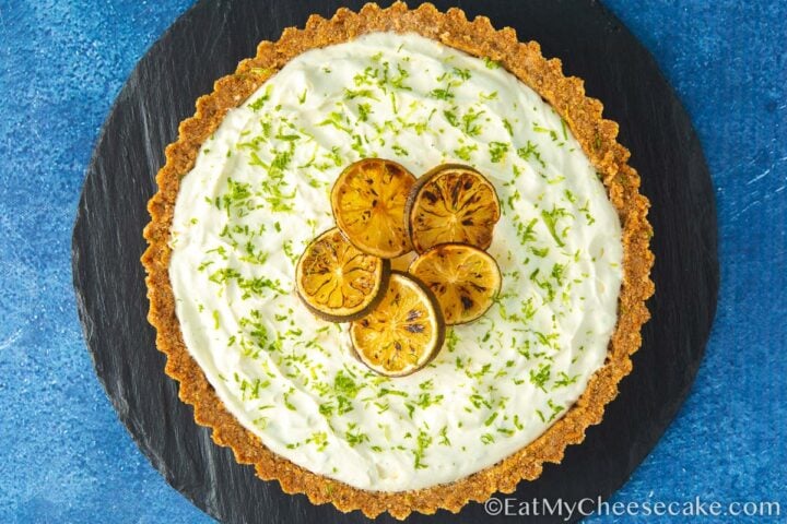 Top view of a key lime cheesecake pie decorated with lime slices and lime zest.