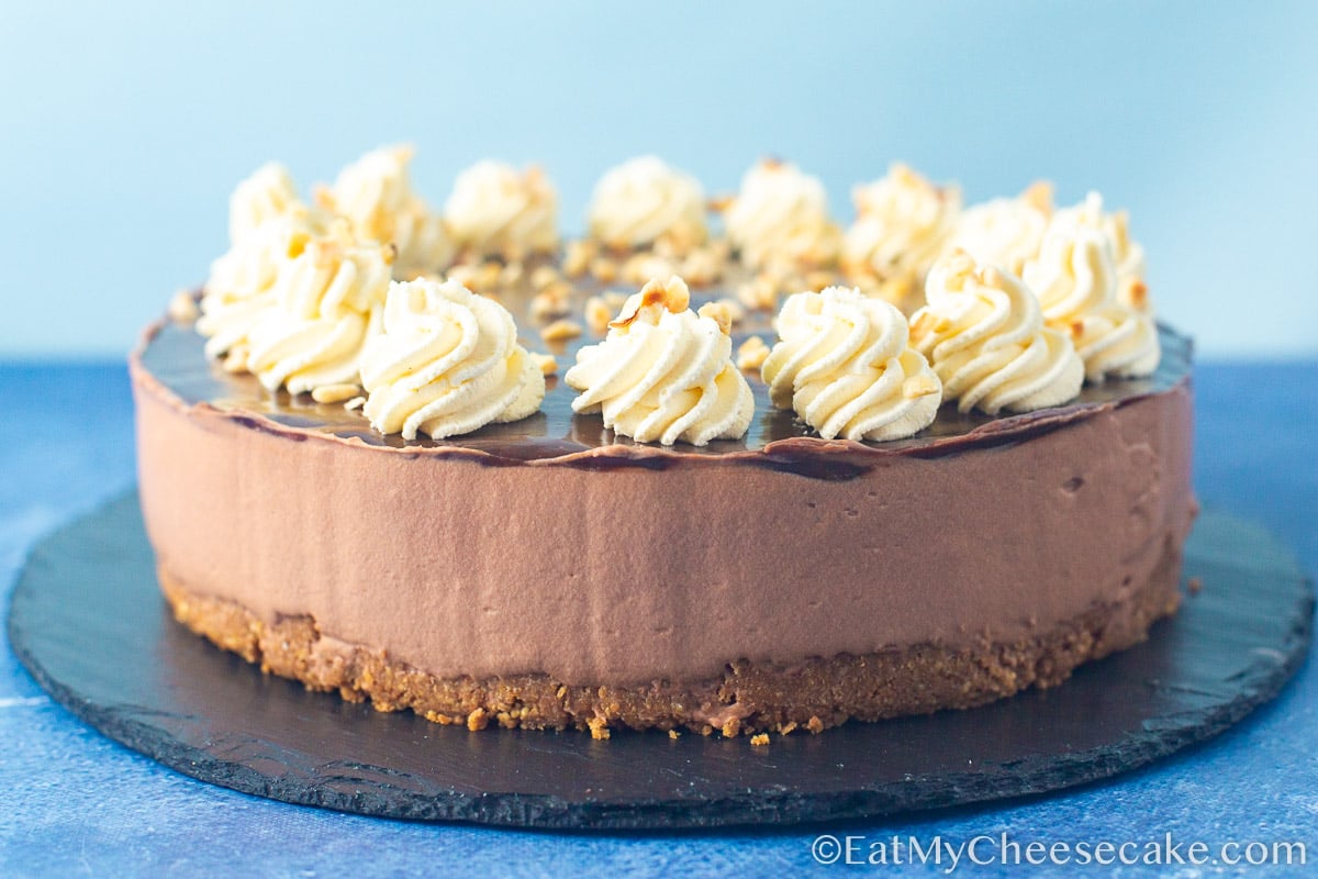 Nutella cheesecake with cream swirl decorations and sprinkled with nuts.