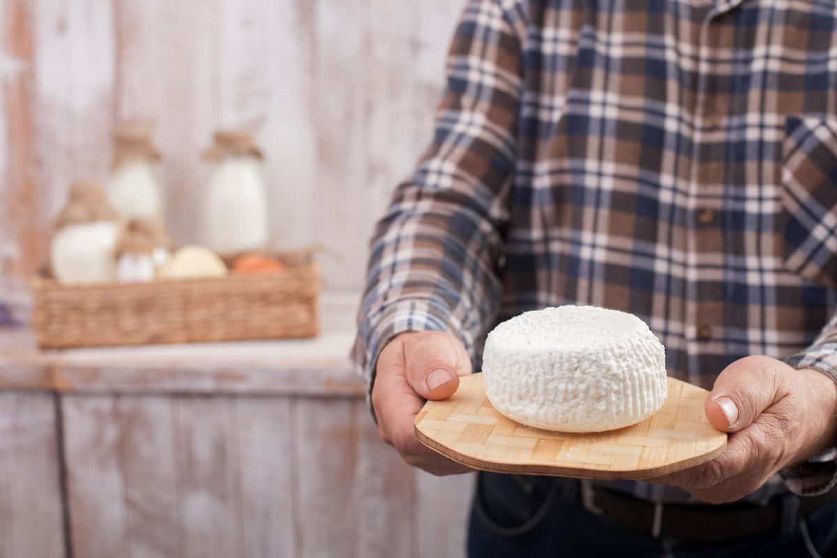 Man holding wooden plate with farmers cheese.