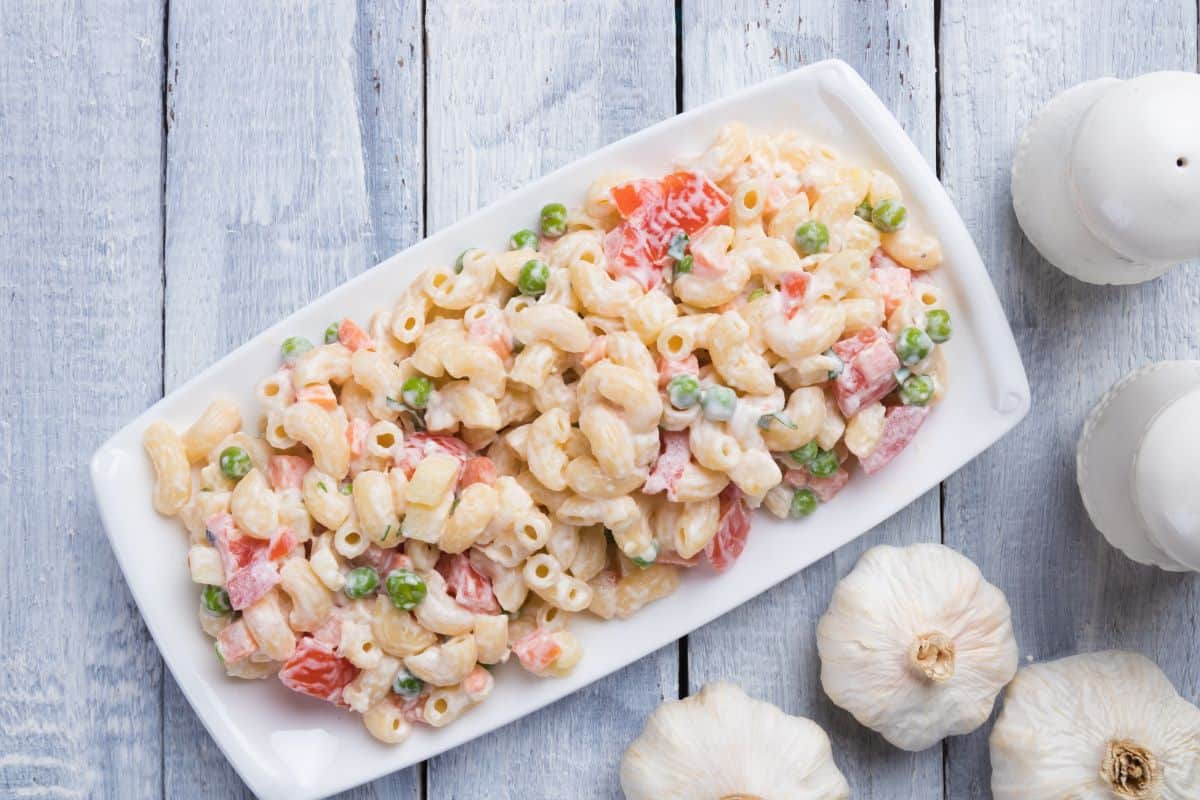 Macaroni salad with a wood panel background.