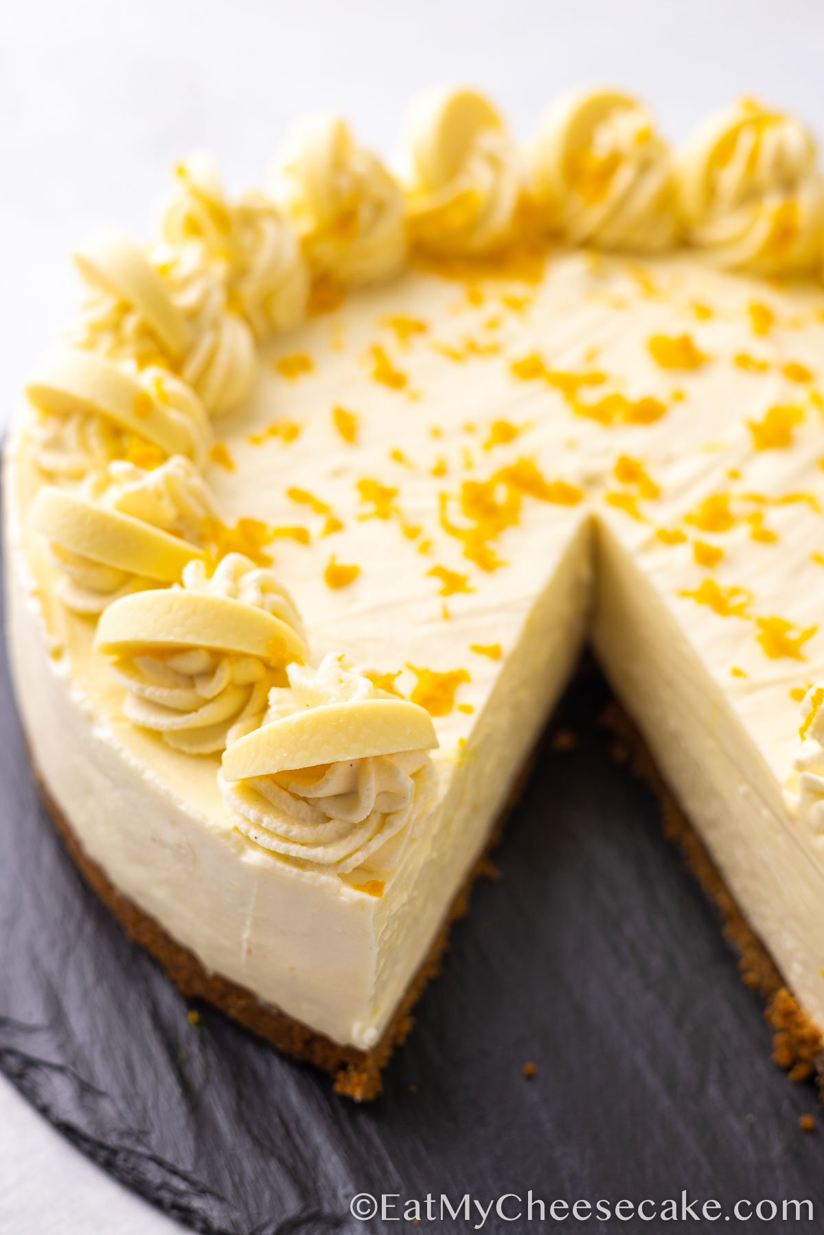 white chocolate orange cheesecake with a slice taken out.