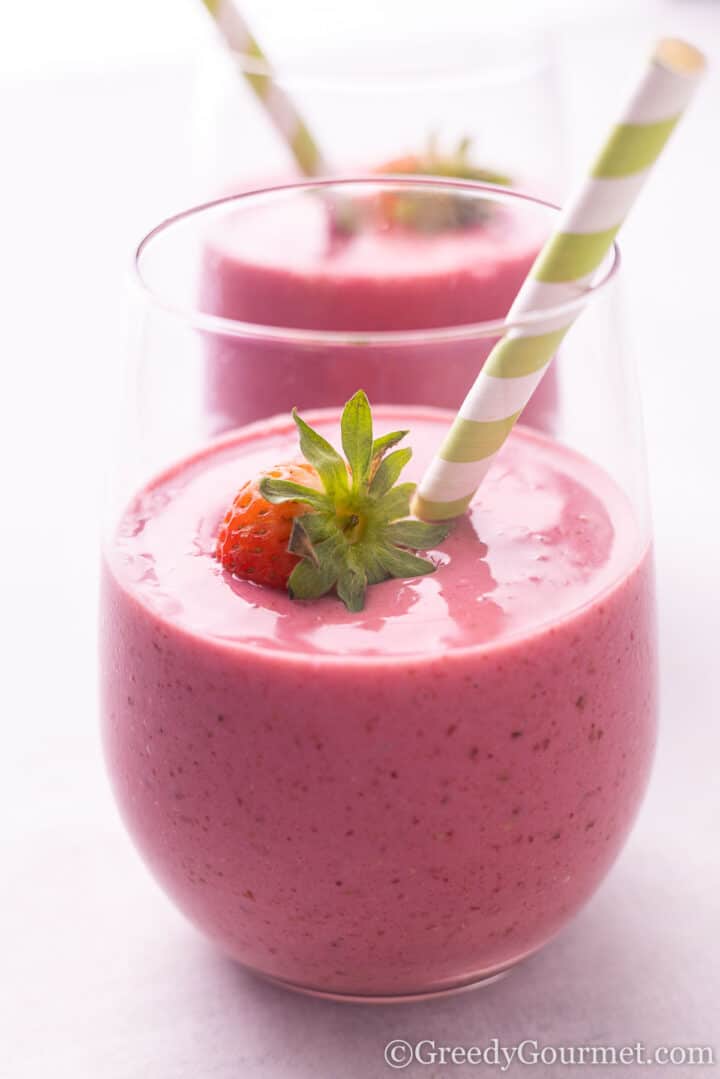 Strawberry Blackberry Banana Smoothie in a glass with a green paper straw.