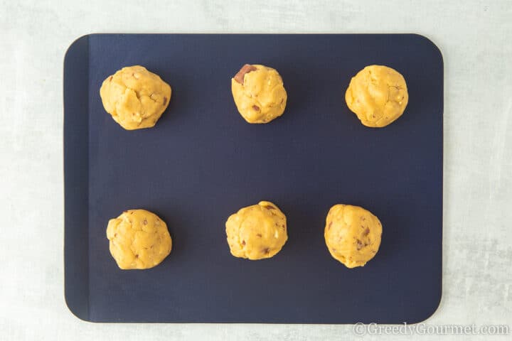 raw cookie dough balls on zyliss non stick baking sheet.