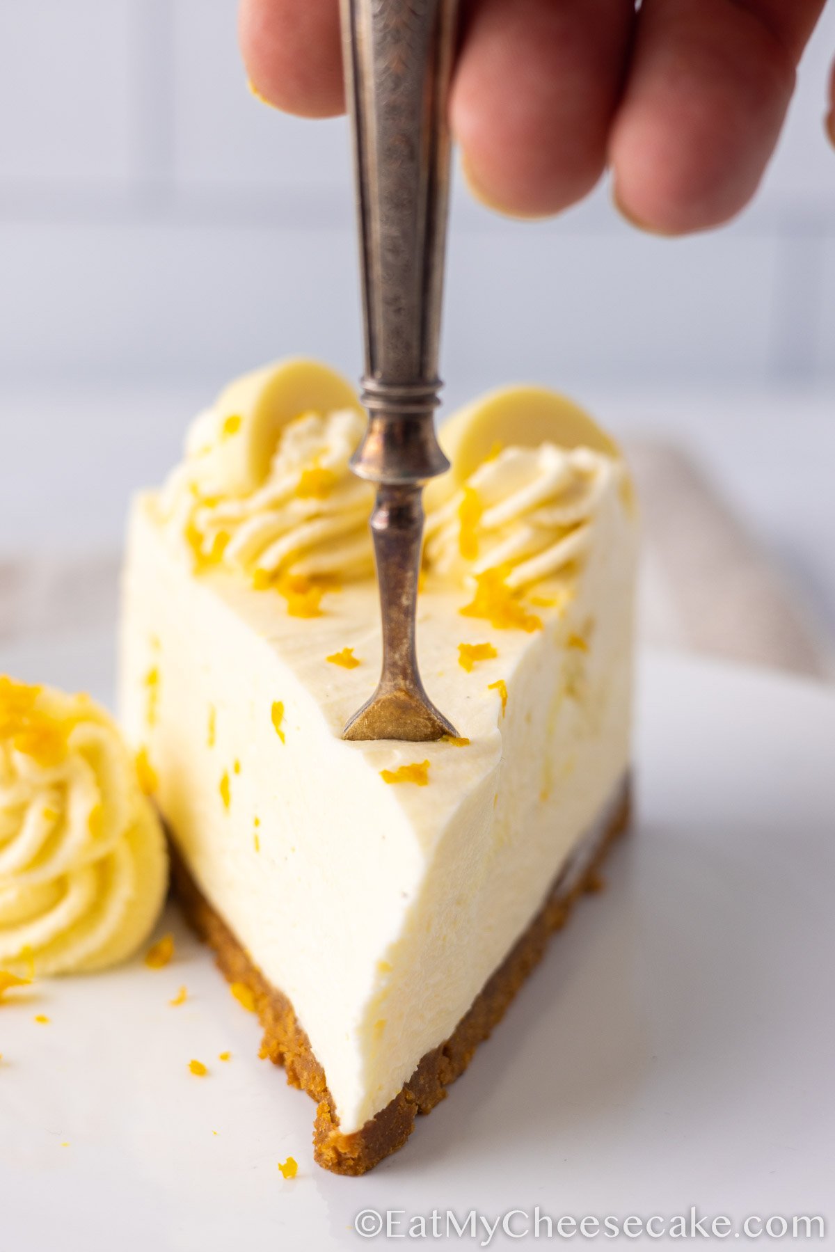 slice of white chocolate orange cheesecake decorated with orange peel.