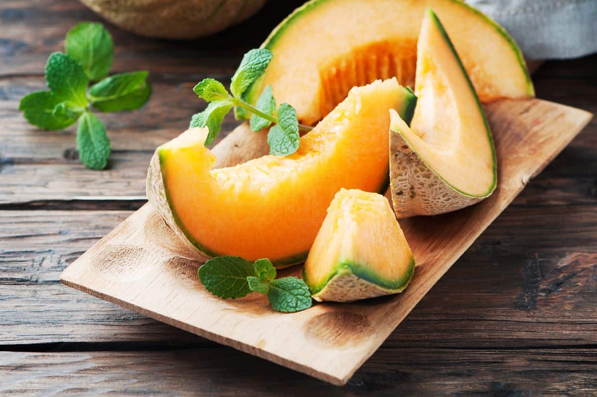 Cantaloupe slices on wooden board.