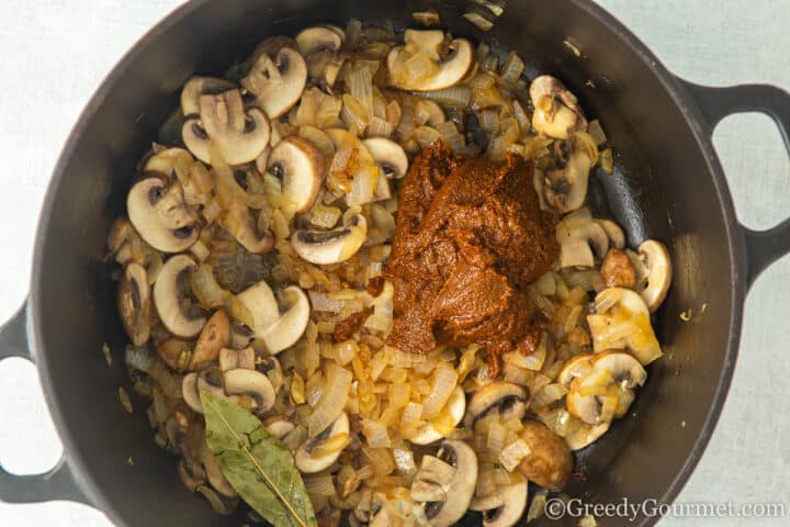 curry paste, mushrooms and onions in a pan.