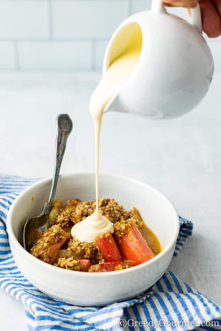 pouring custard on rhubarb and pear crumble.