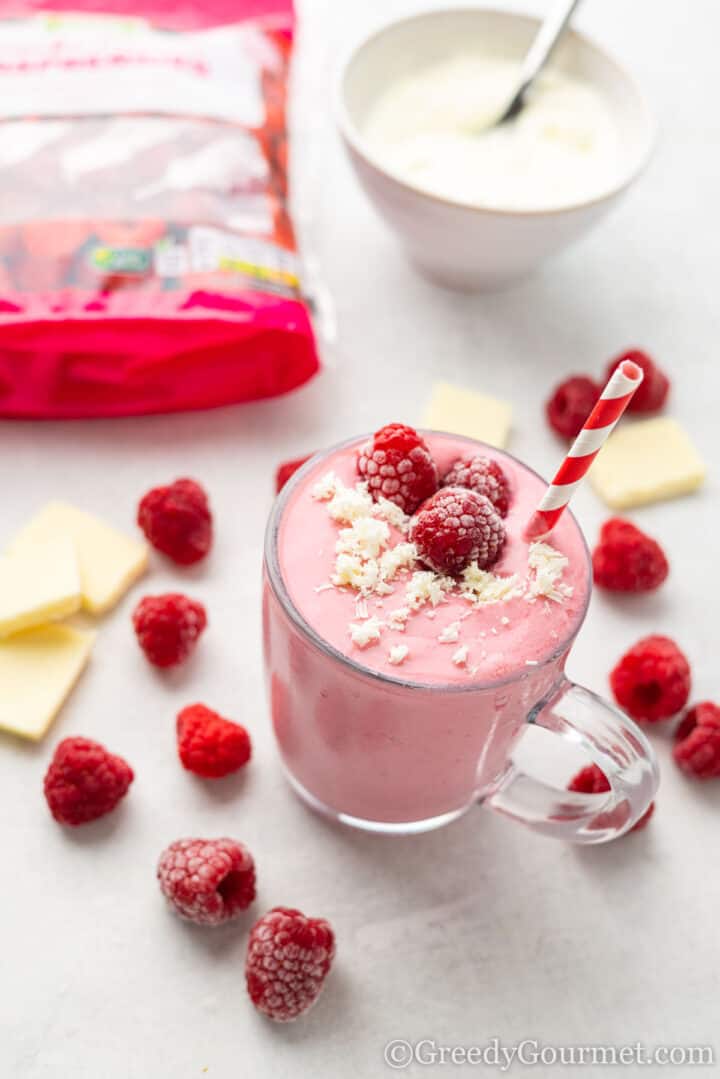 smoothie with white chocolate shavings and raspberries on top and in background. 