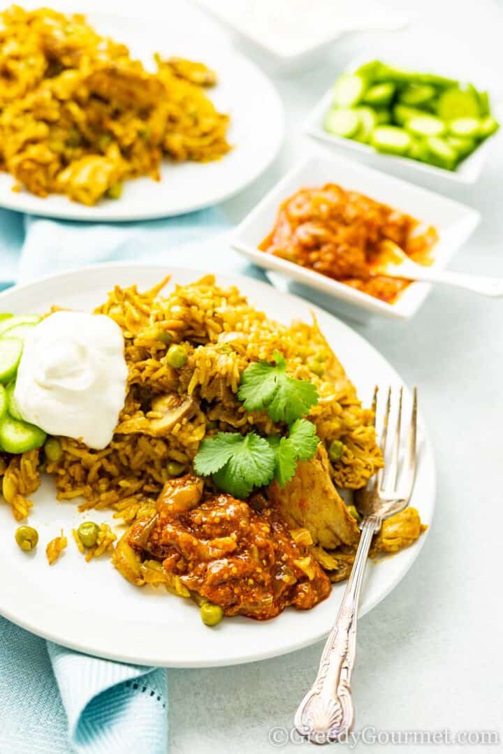 turkey biryani served of a plate with side dishes.