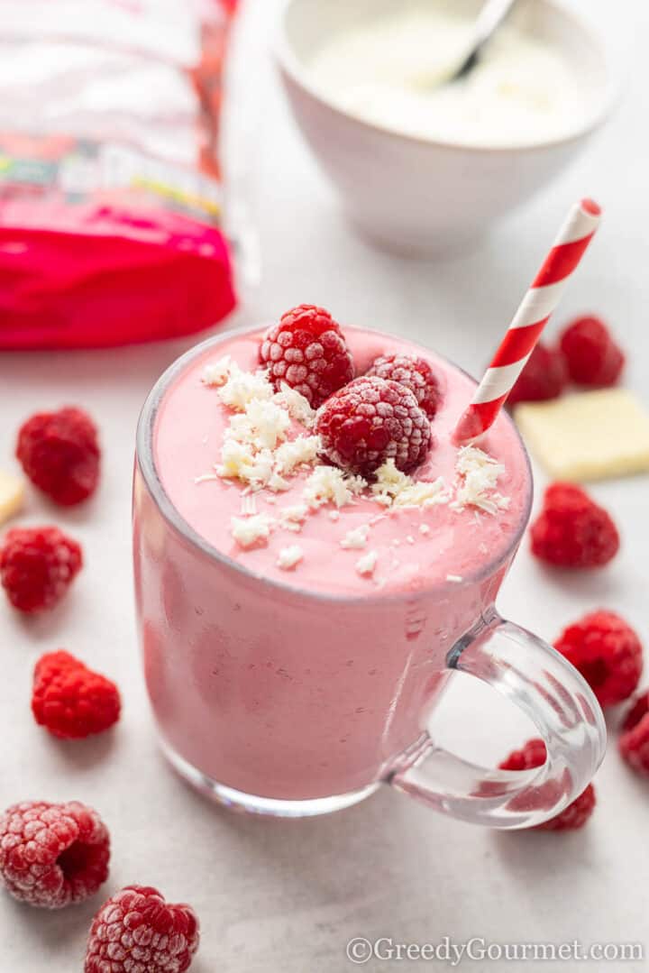 smoothie with white chocolate shavings and raspberries on top.