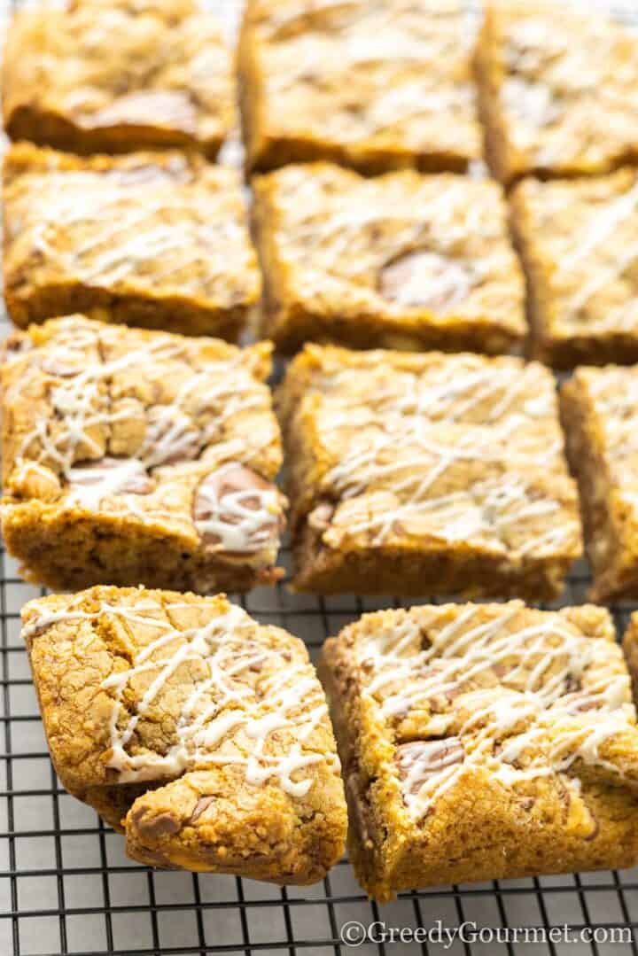kinder cookie bars drizzled with white chocolate on cooling rack