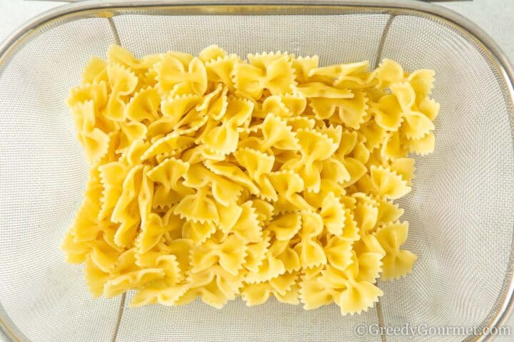 cooked bowtie pasta in strainer.