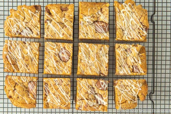 kinder cookie bars drizzled with chocolate on cooling rack.
