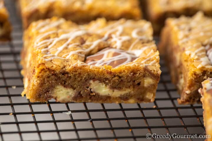 kinder cookie bars drizzled with white chocolate on cooling rack.