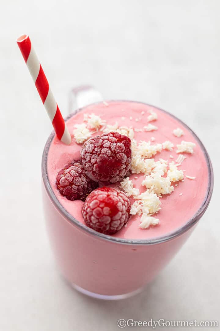 smoothie with white chocolate shavings and raspberries on top.