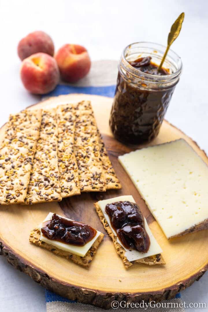 chutney, cheese and crackers on a wooden plate.
