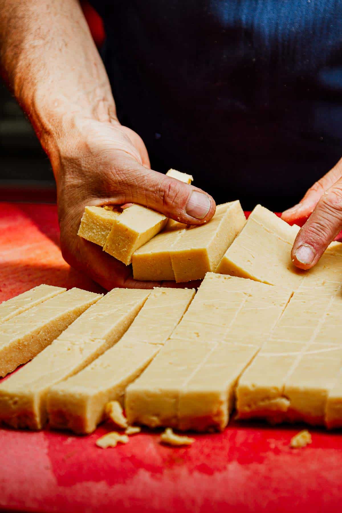 close up of a chefs hands collecting freshly cut panisses for dinner service.