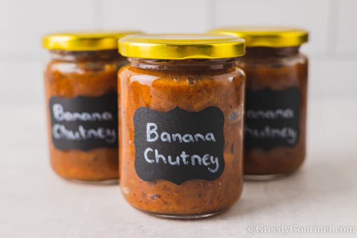 3 jars of banana chutney nexct to each other with black labels.