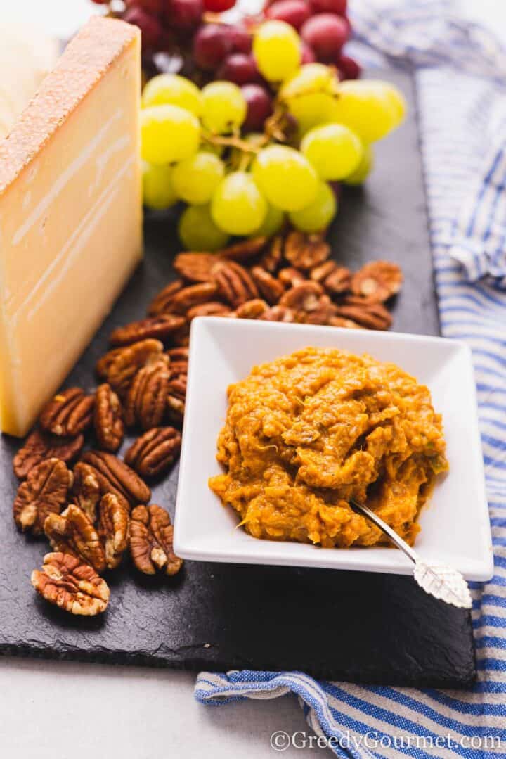 banana chutney with cheese, grapes and walnuts on a cheeseboard.