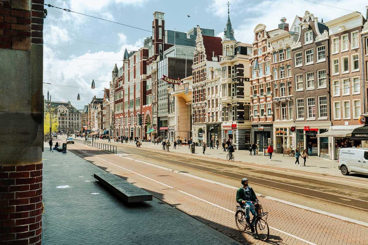 The Damrak avenue with people walking and cycling.