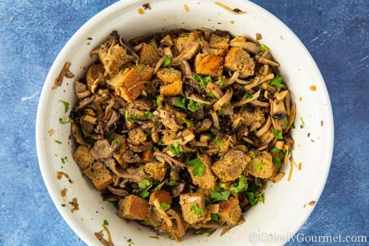 mixing mushrooms and bread cubes in a bowl.